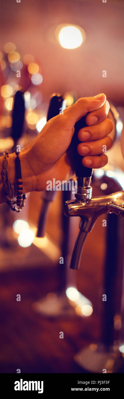Bartender hands using beer tap in pub Stock Photo