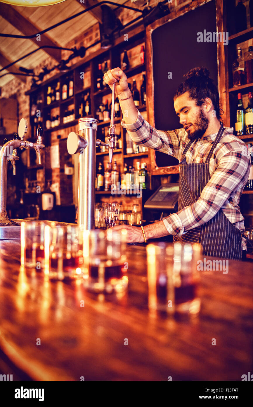 Waiter using beer tap at counter Stock Photo