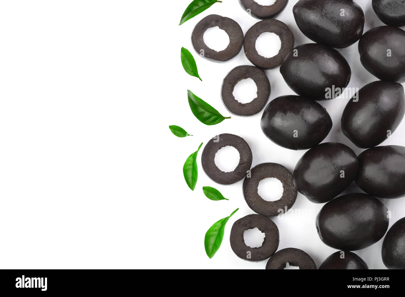 whole and sliced black olives decorated with leaves isolated on white background with copy space for your text. Top view Stock Photo