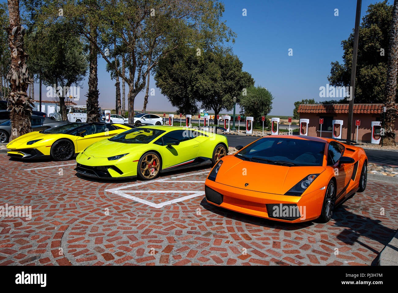 Three Lamborghini sports cars parked in front of a Tesla Super Charger station, Harris Ranch (3O8), Coalinga, California, United States of America Stock Photo