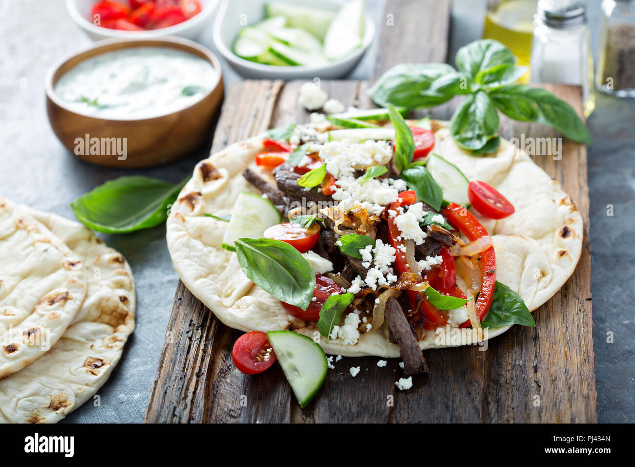 Flatbread with beef, feta cheese and vegetables with tzatziki sauce