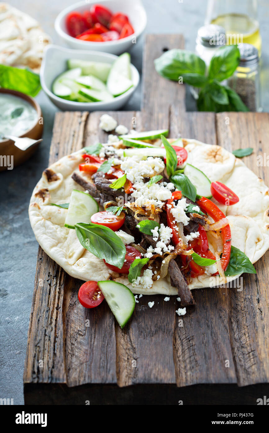 Flatbread with beef, feta cheese and vegetables with tzatziki sauce