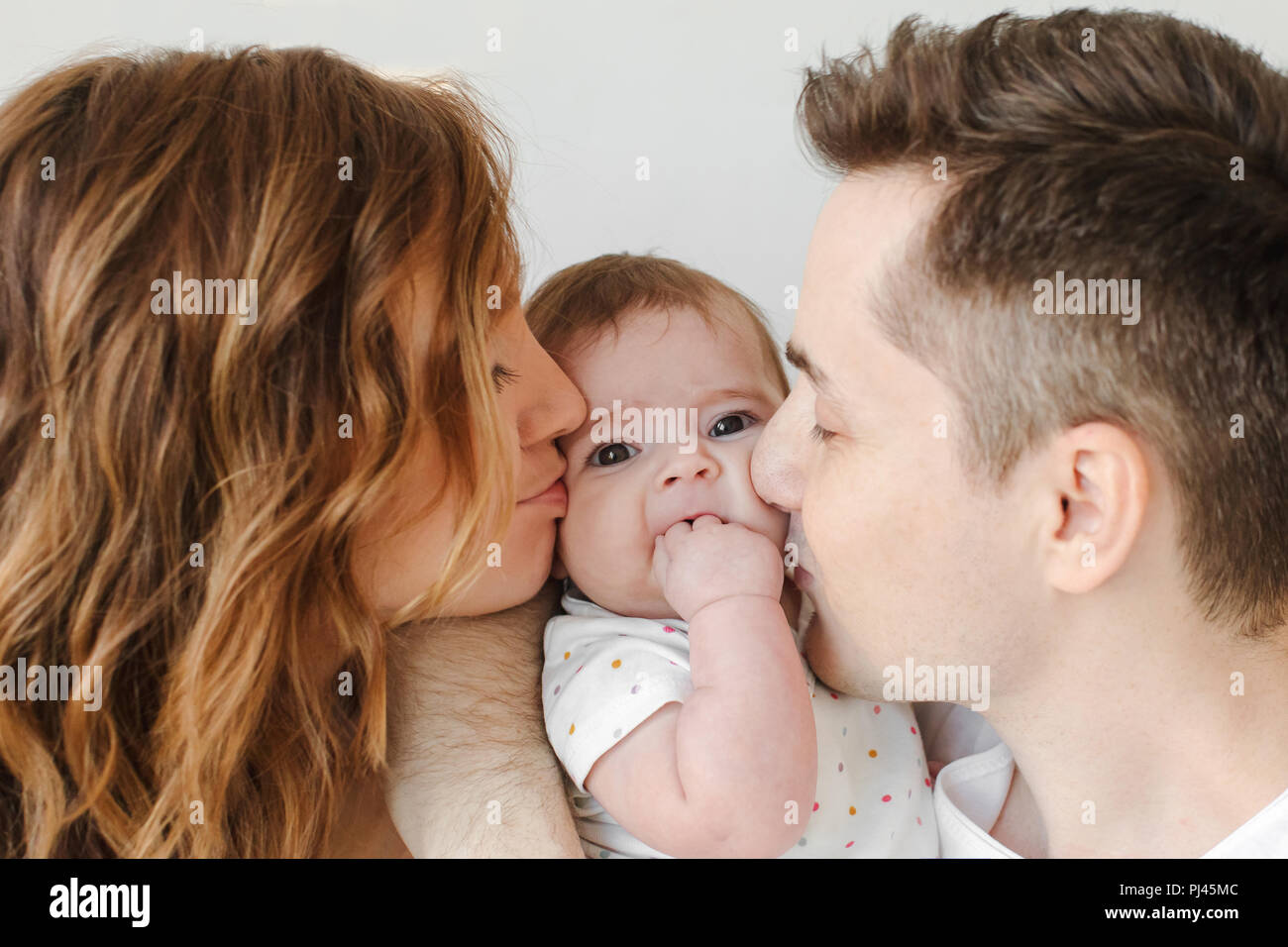 Parents kissing baby in cheeks Stock Photo