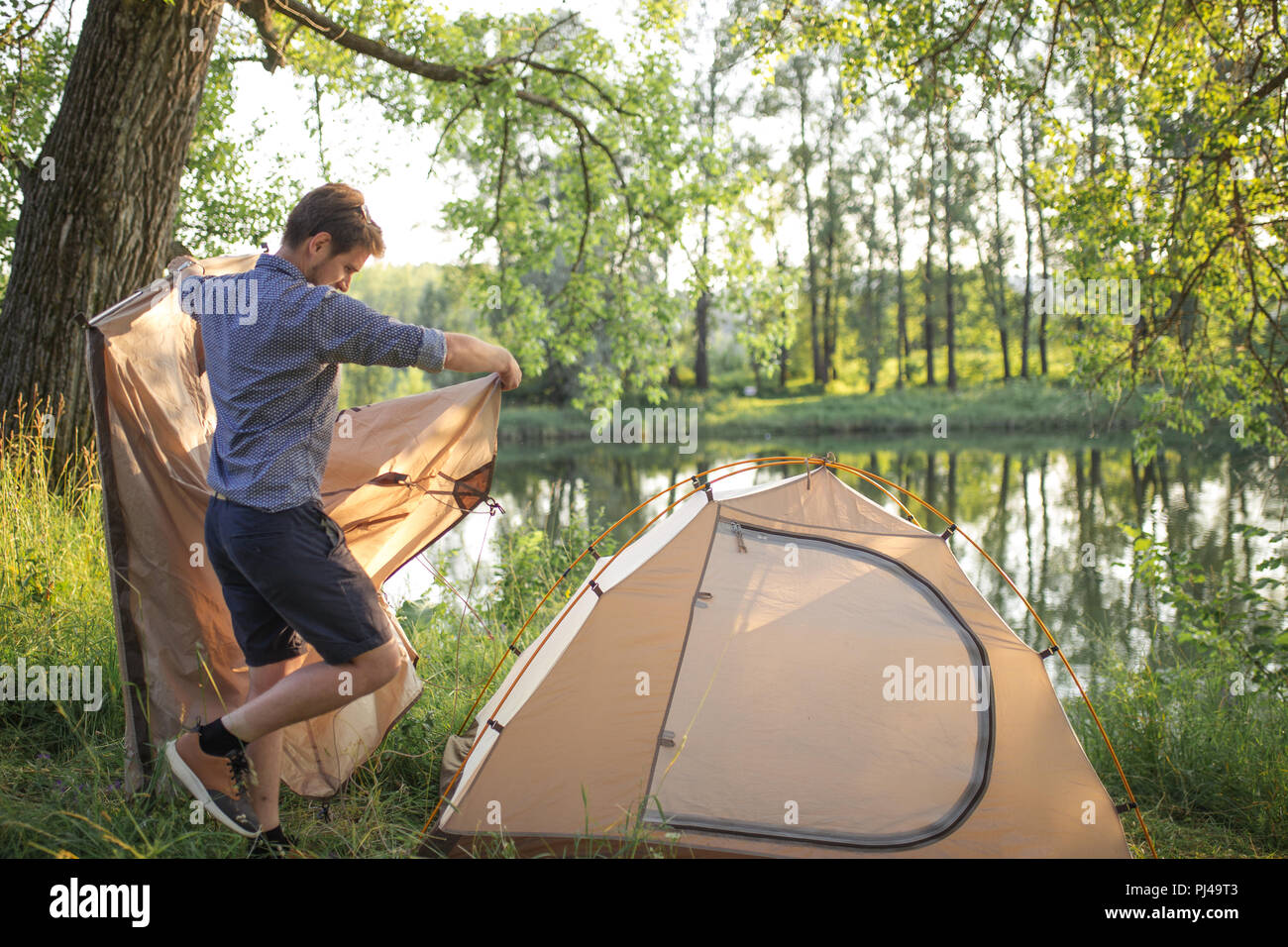 Young handsome man is putting up a tent Stock Photo
