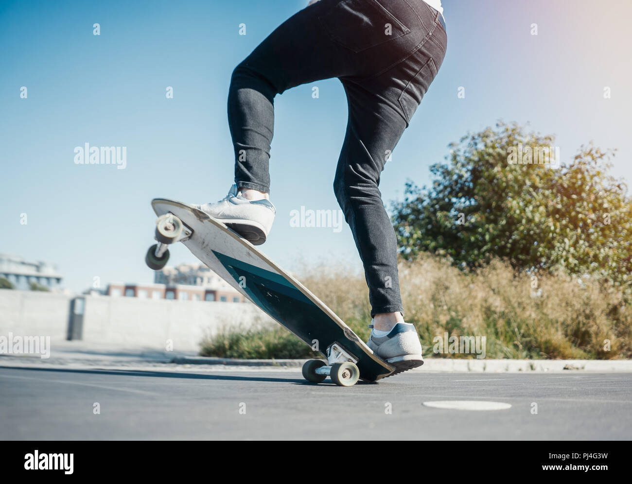 Young attractive man riding and jumping longboard in the park. Stock Photo