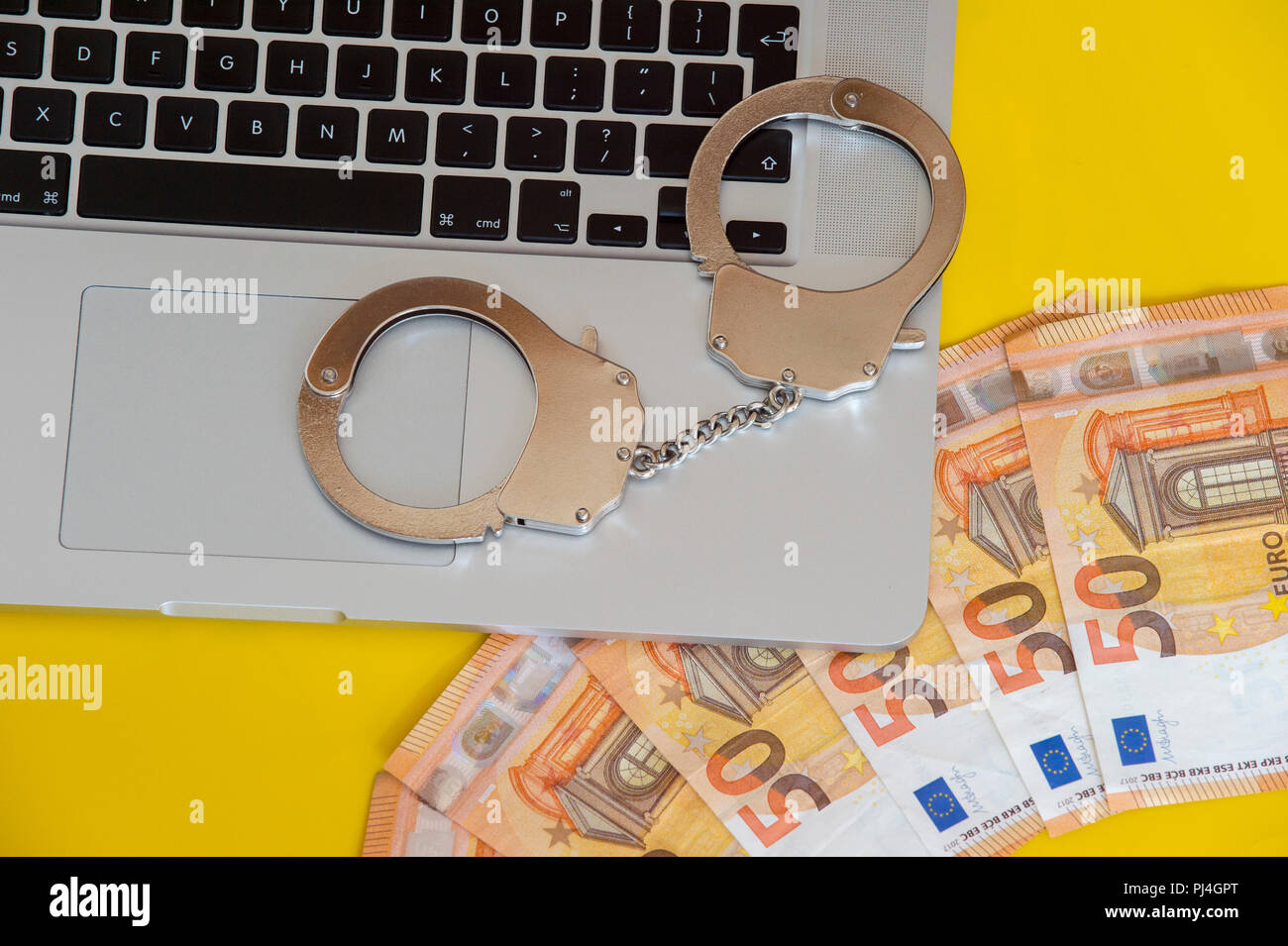 Money under handcuffs on the laptop keyboard. Hacker crime concept. Stock Photo