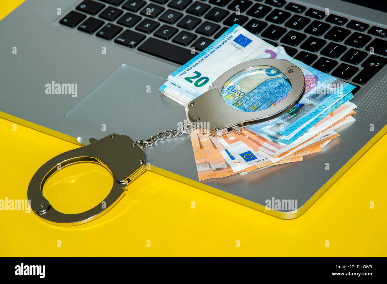 Money under handcuffs on the laptop keyboard. Hacker crime concept. Stock Photo
