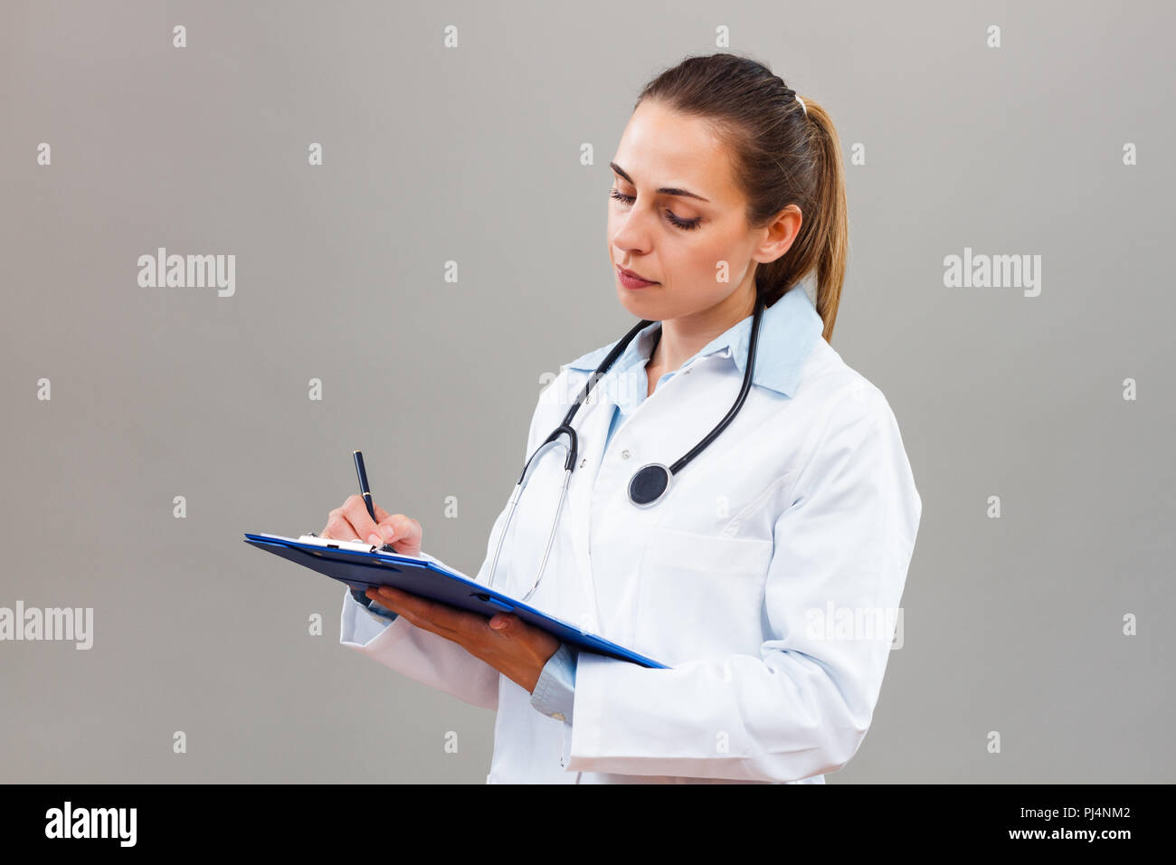 Beautiful female doctor writing notes Stock Photo - Alamy