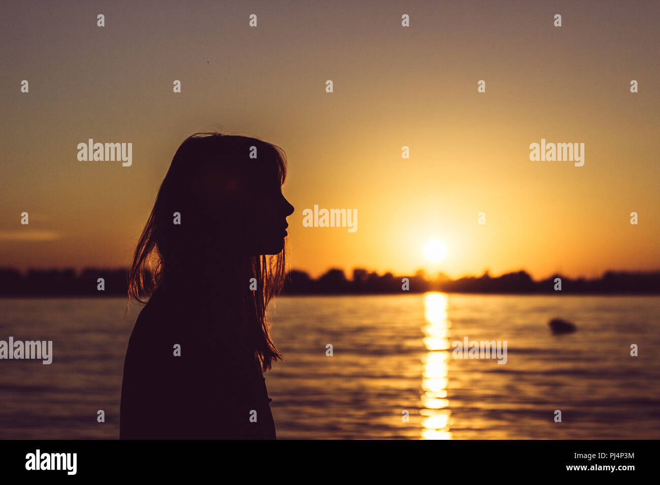 Woman playing with sand on beach with sunset Stock Photo