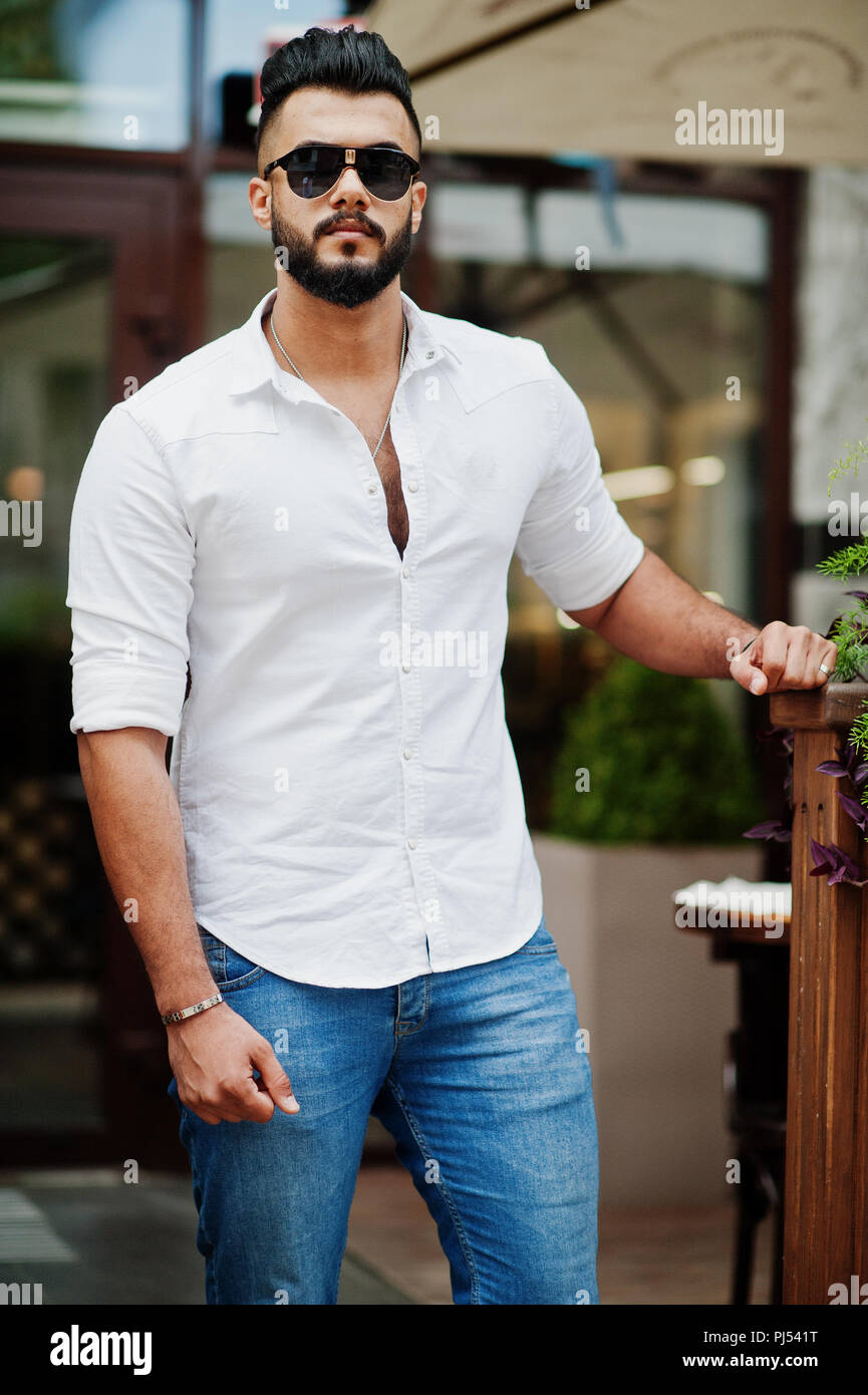 Stylish tall arabian man model in white shirt, jeans and sunglasses posed  at street of city. Beard attractive arab guy Stock Photo - Alamy