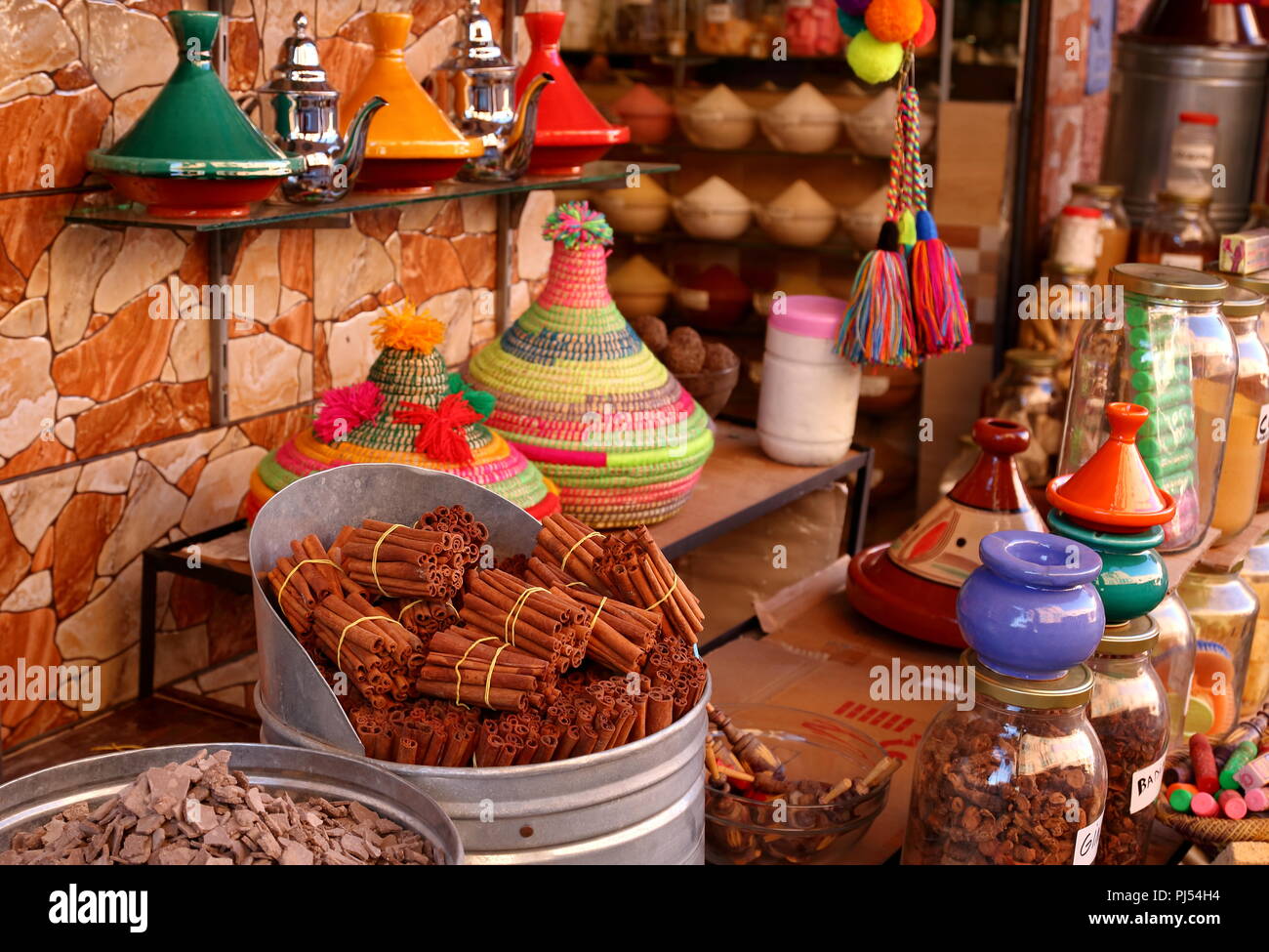 Colorfoul street market stand in Marrakech, Morocco, with cinnamon sticks, handicraft traditional souvenirs, typical dishes made of clay, cosmetics. Stock Photo