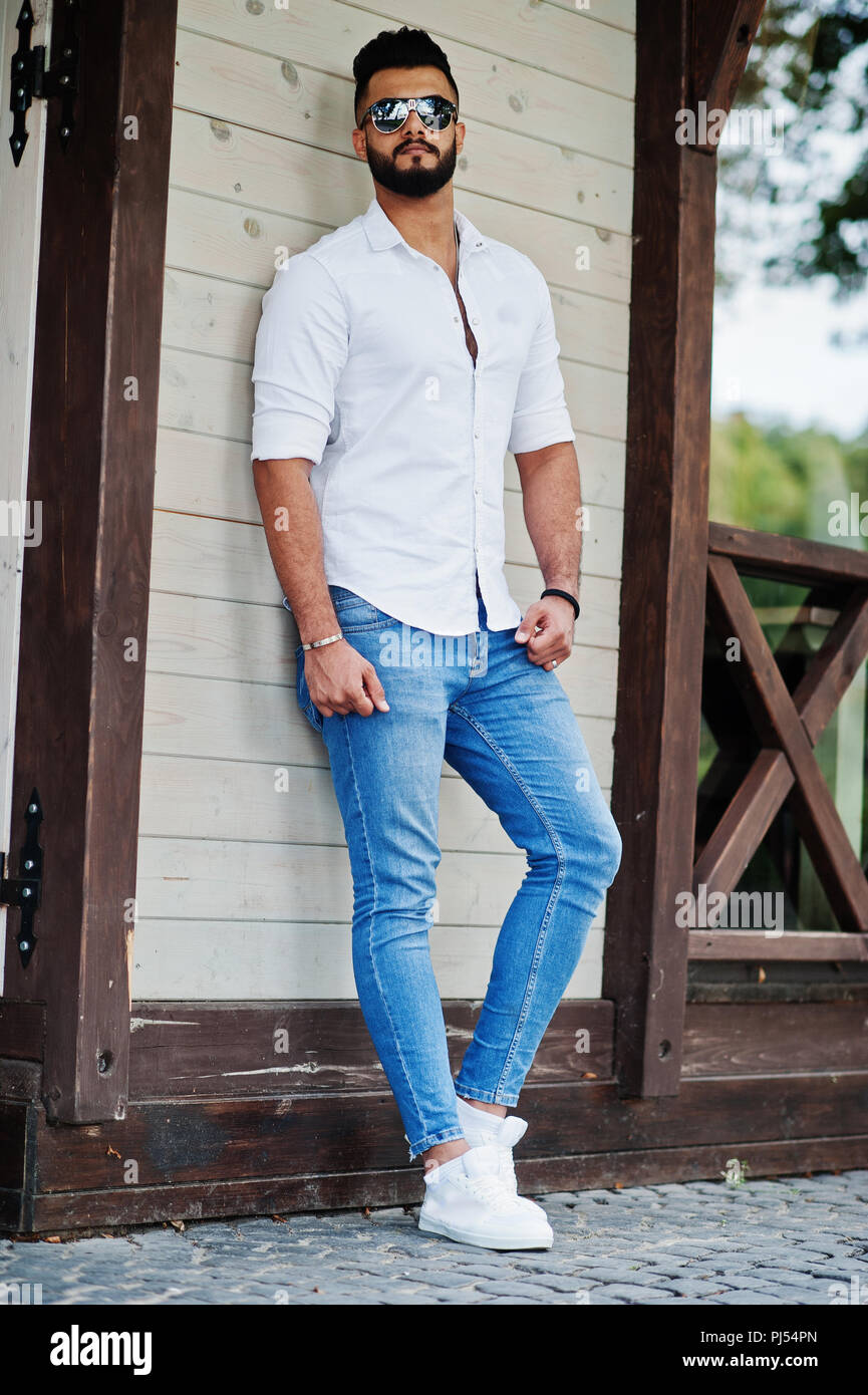 Stylish tall arabian man model in white shirt, jeans and sunglasses posed  at street of city. Beard attractive arab guy Stock Photo - Alamy