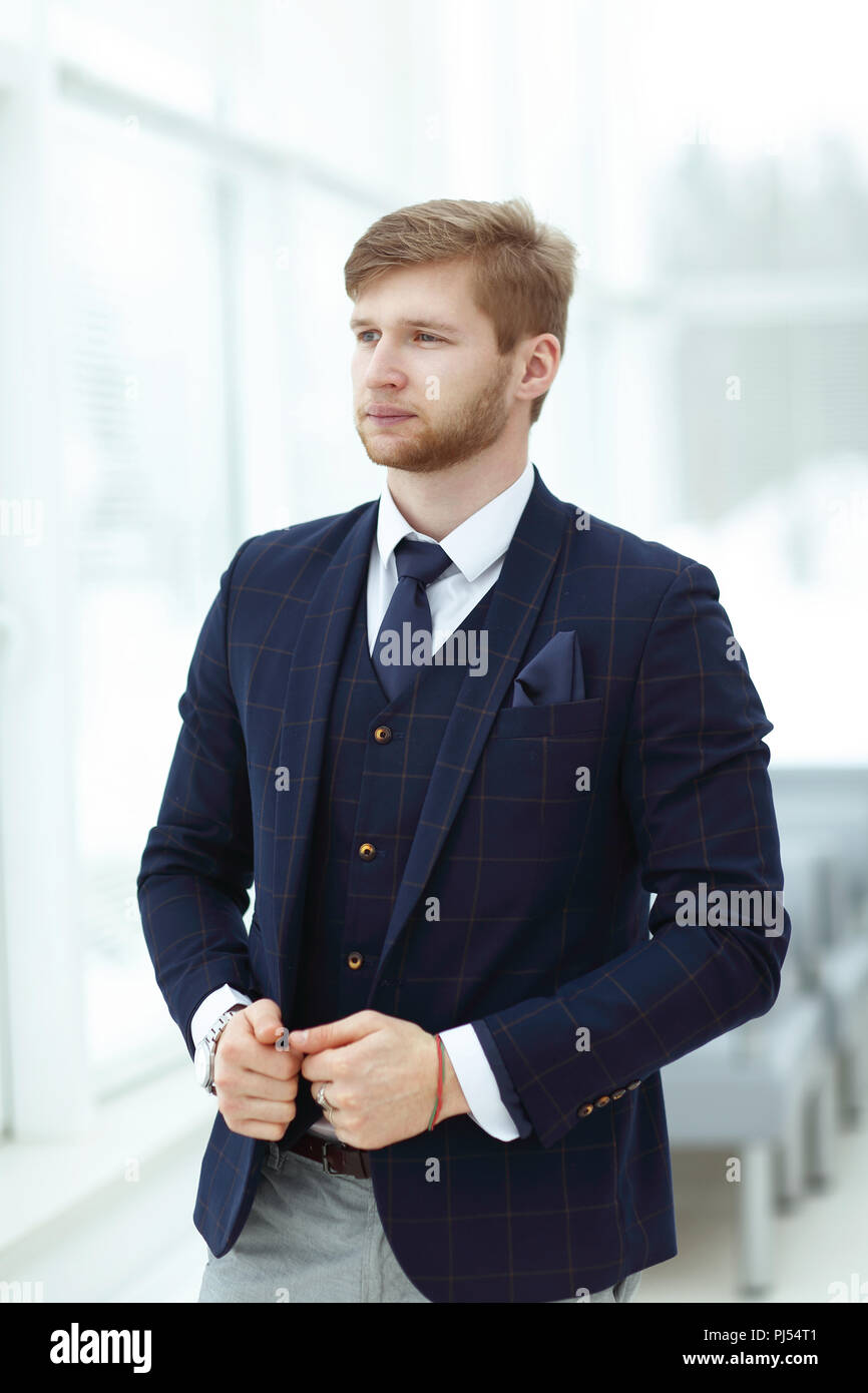 Portrait of an elegant young businessman standing with arms crossed in ...