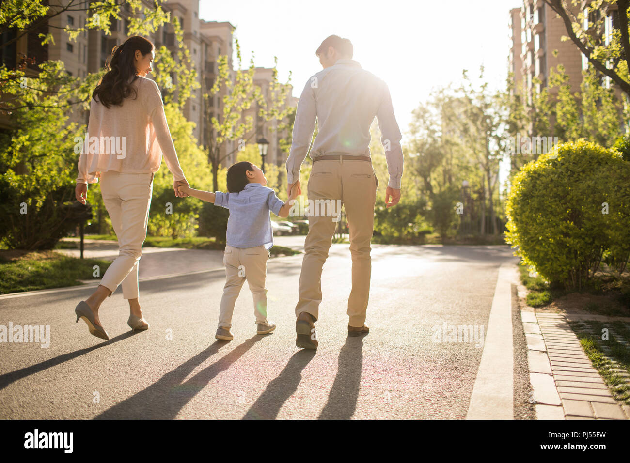 Happy young family holding hands walking Stock Photo - Alamy