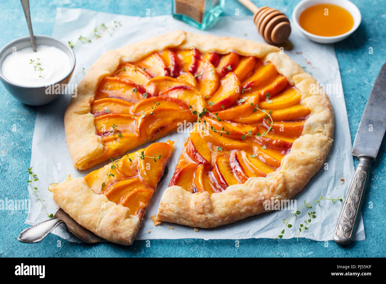 Peach galette, pie, cake with honey and berry on a blue background. Stock Photo