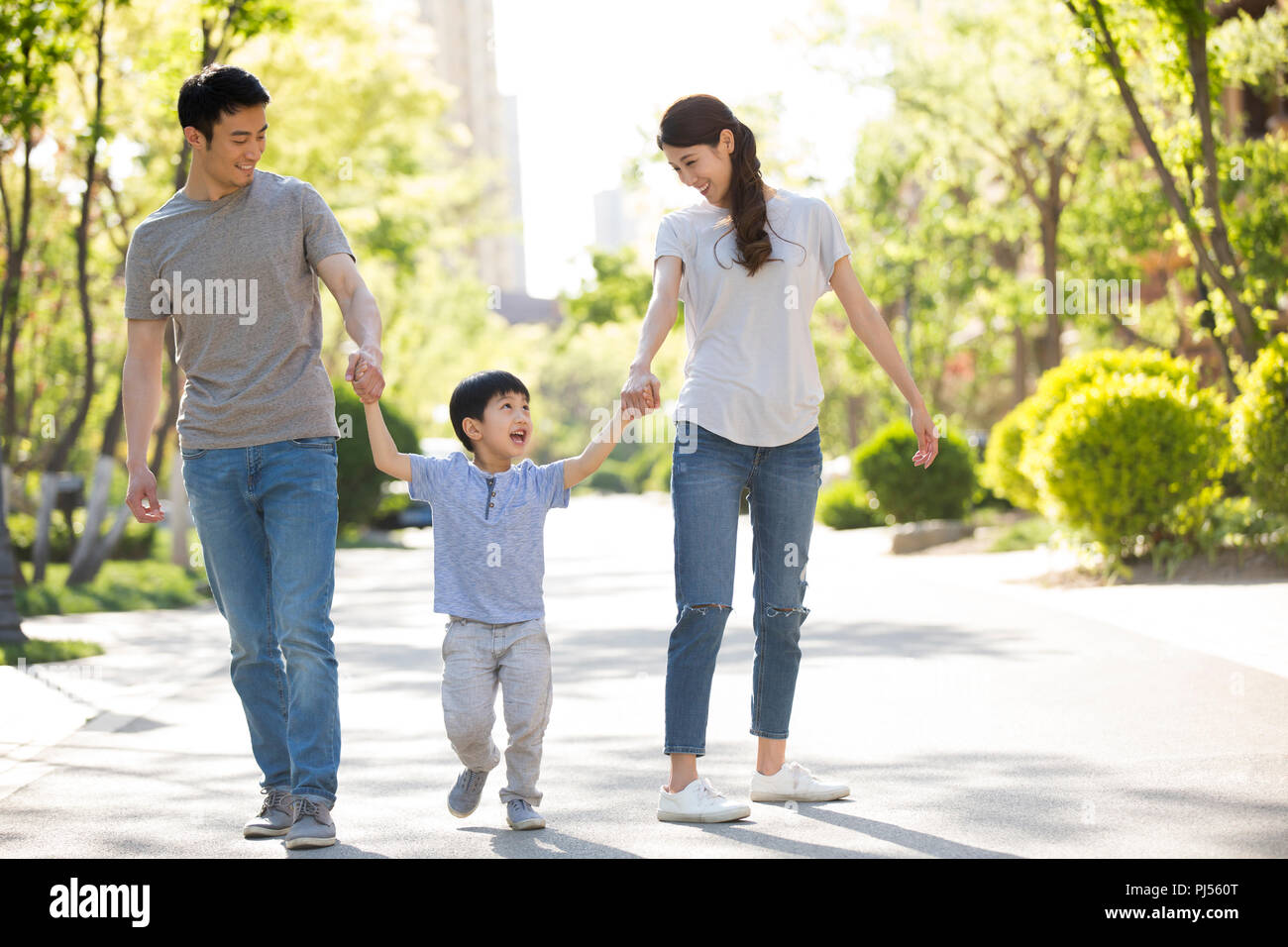 Happy young family holding hands walking Stock Photo - Alamy