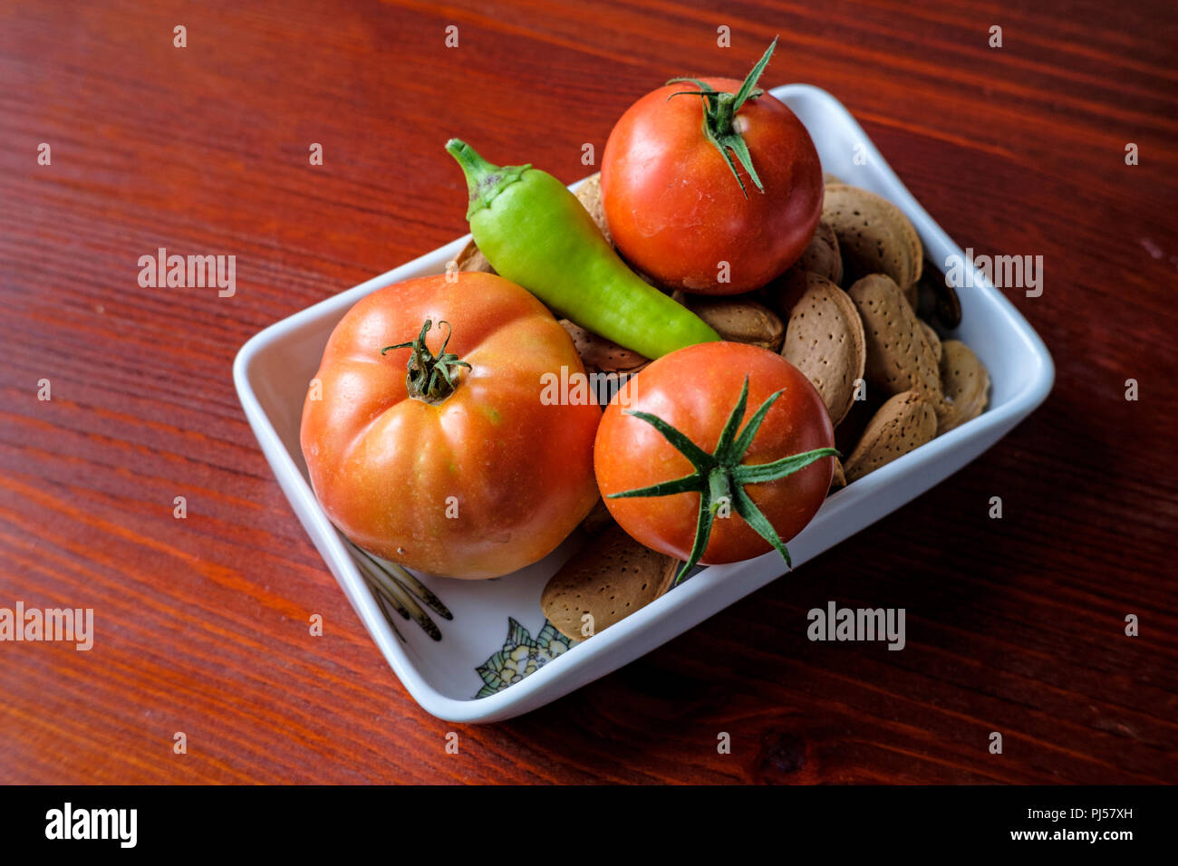 Tomatoes, peppers and almonds on a wooden table Stock Photo