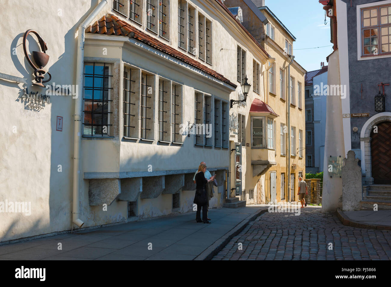 Tallinn street, view of two middle aged tourists standing outside the oldest pharmacy in Europe - the Apteek (1422) in Tallinn Old Town, Estonia. Stock Photo