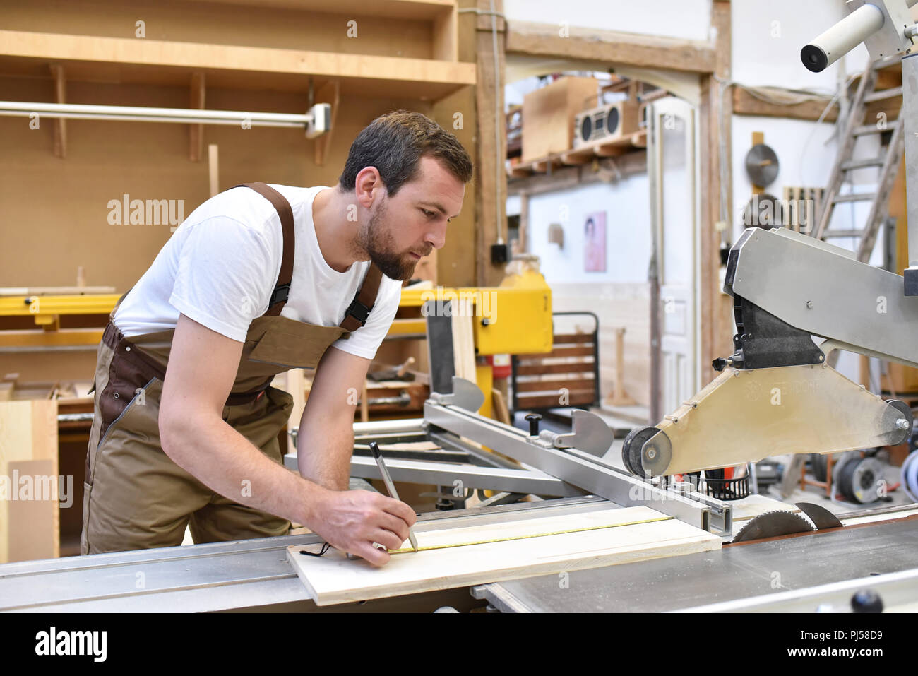 carpenter works in a joinery - workshop for woodworking and sawing Stock Photo
