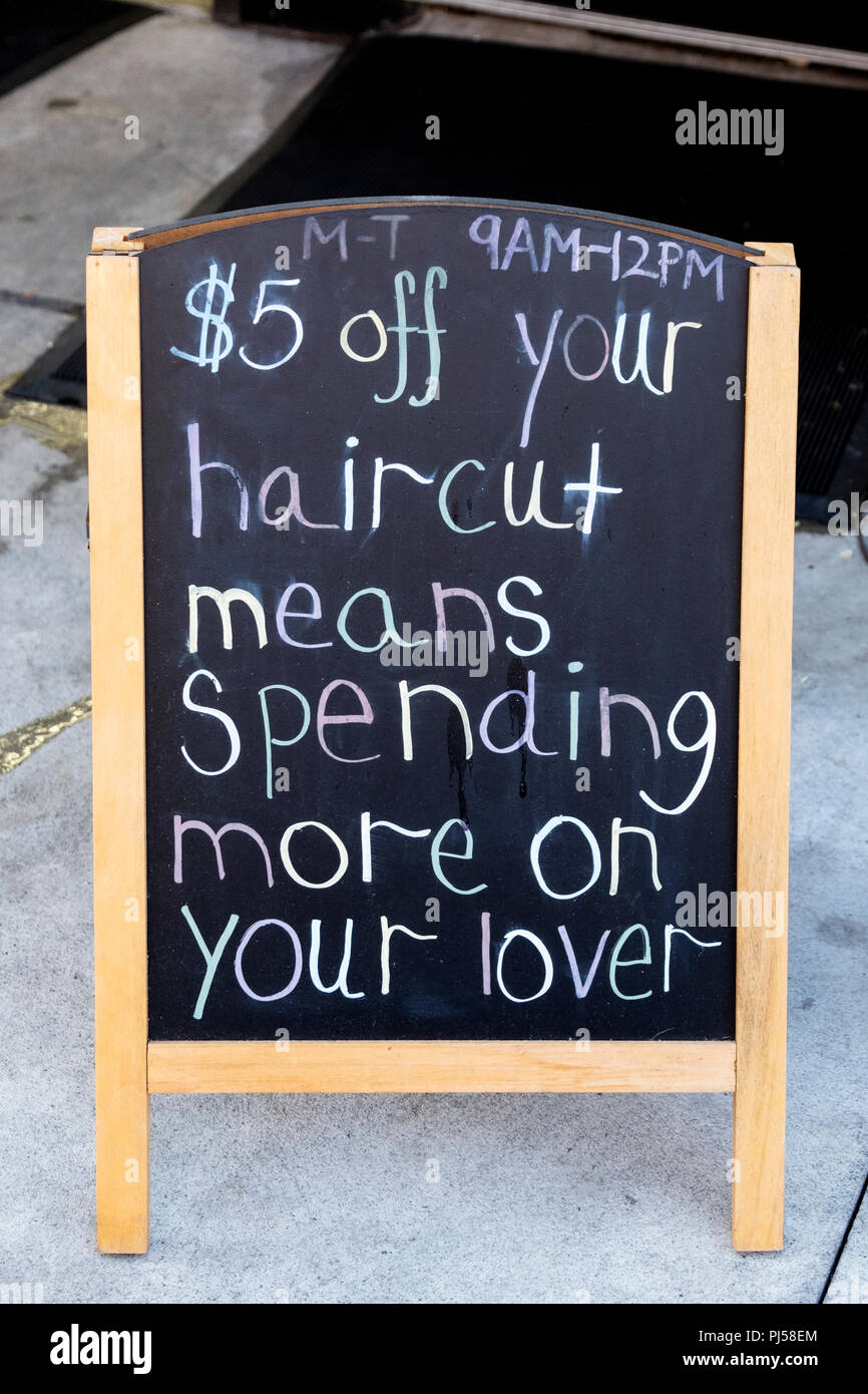 A funny sign outside a 7th avenue Chelsea, NYC barber shop advertising that an on sale haircut will leave you money for your lover.. Stock Photo
