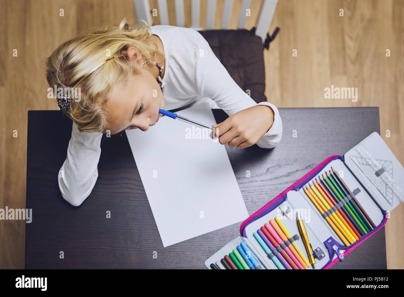 Cute girl comtemplation about her homework for elementary school at home. Stock Photo