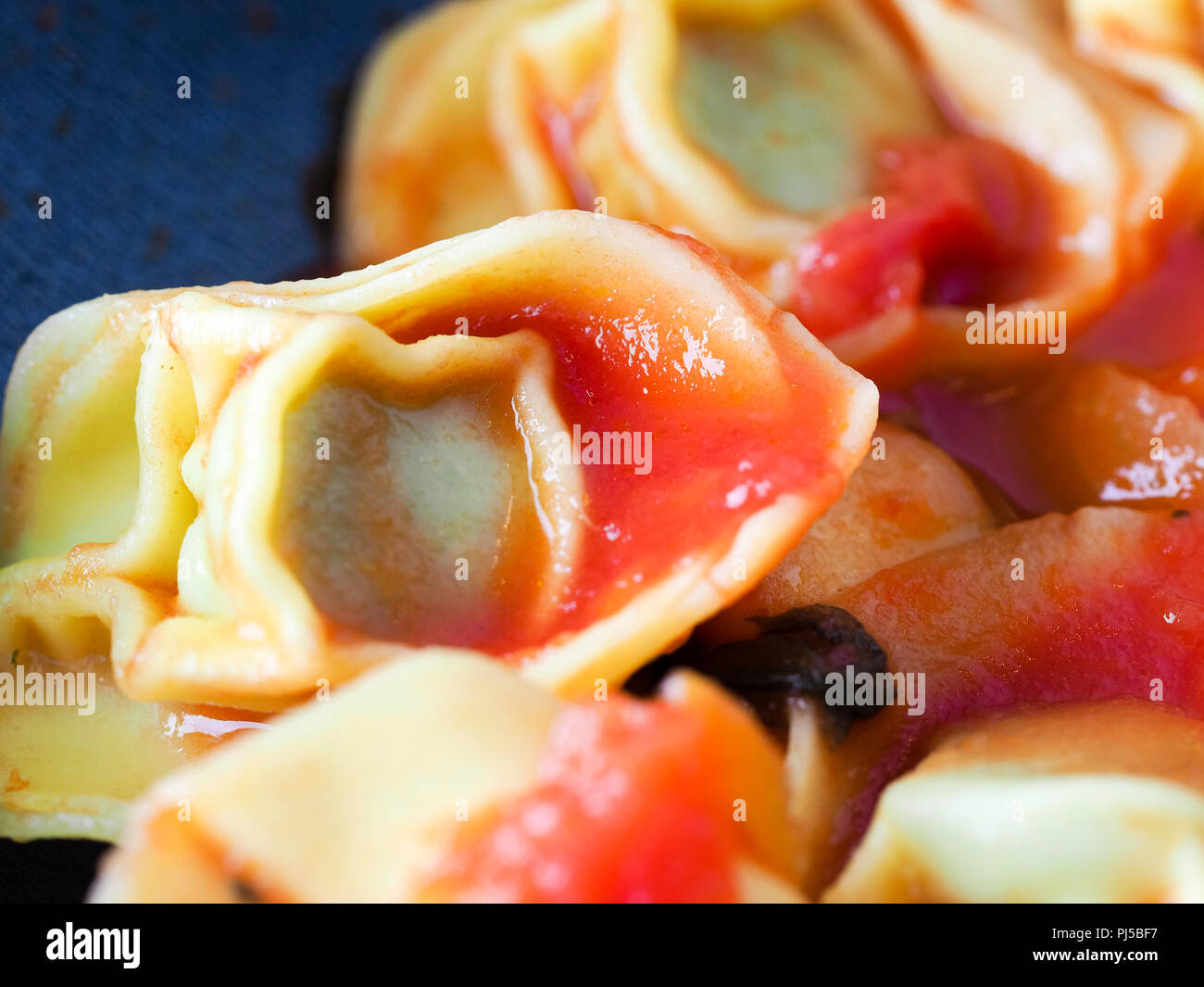 Cooking lunch at home, spinach and ricotta cheese tortellini stuffed italian pasta with tomato
