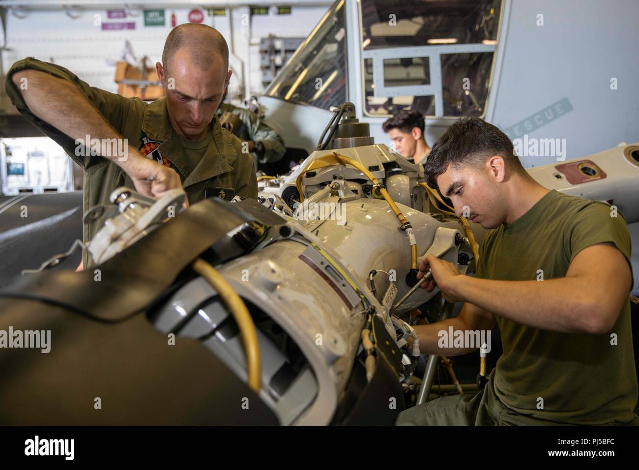 180831-N-SZ865-0075 ATLANTIC OCEAN (Aug. 31, 2018) Sgt. Taylor Stevens,  left, and Lance Cpl. Samuel McBride perform maintenance on the left-hand  hub of a MV-22 Osprey in the hangar bay of the amphibious