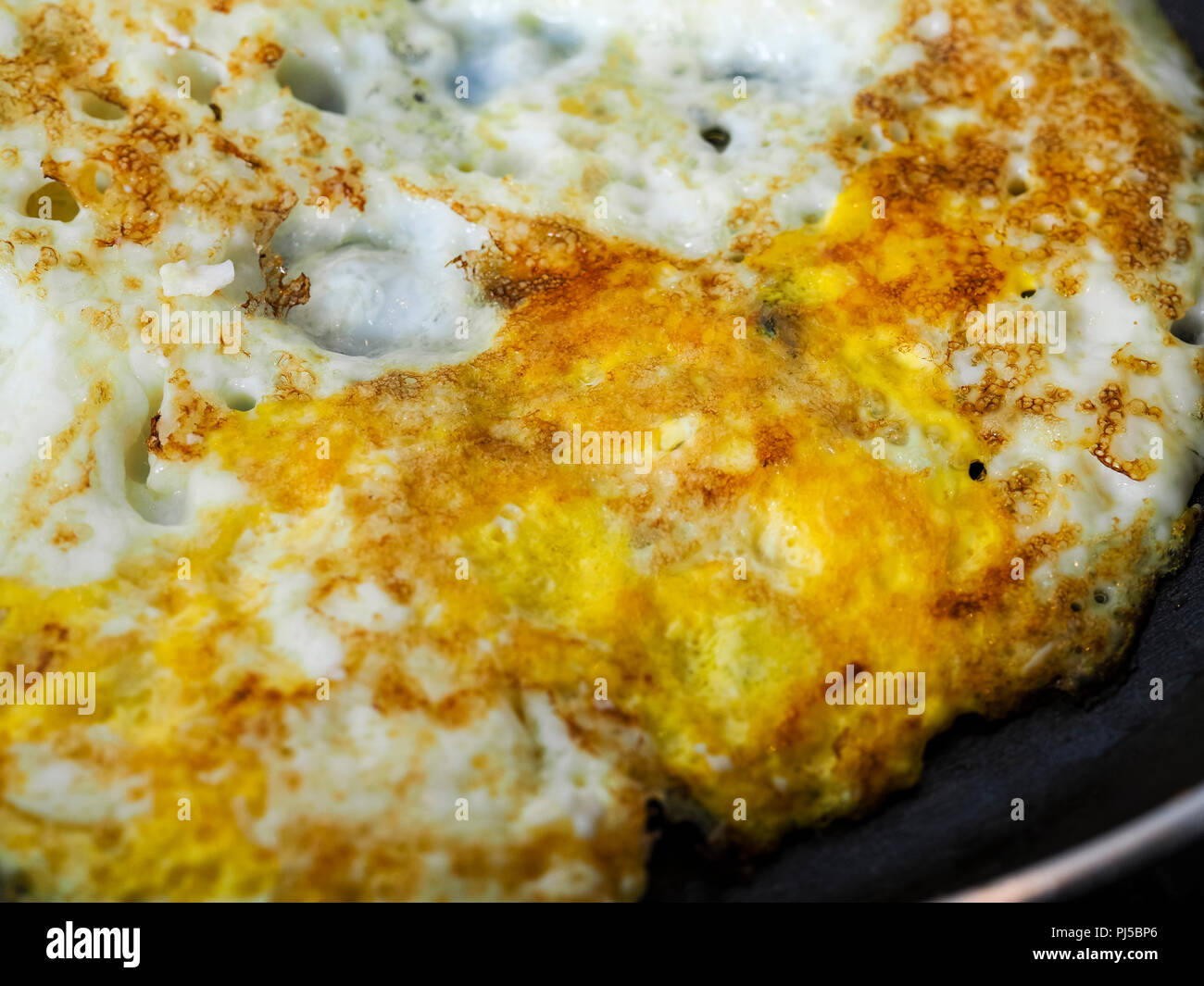 Frying eggs in a dark pan with butter Stock Photo Alamy