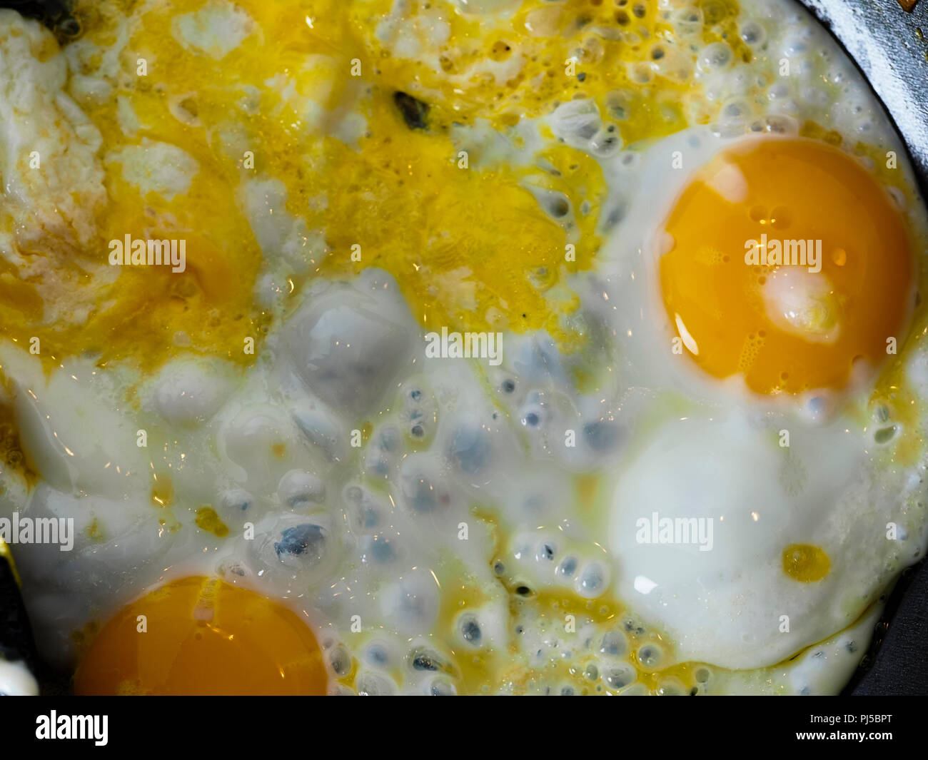 Frying eggs in a dark pan with butter Stock Photo Alamy