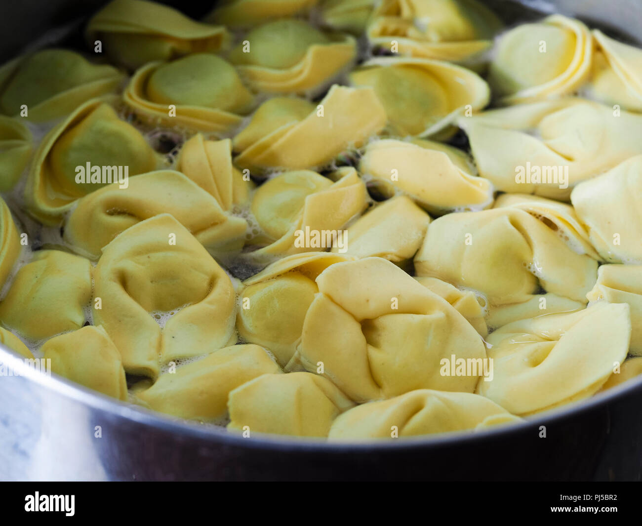 Cooking lunch at home, spinach and ricotta cheese tortellini stuffed italian pasta with tomato