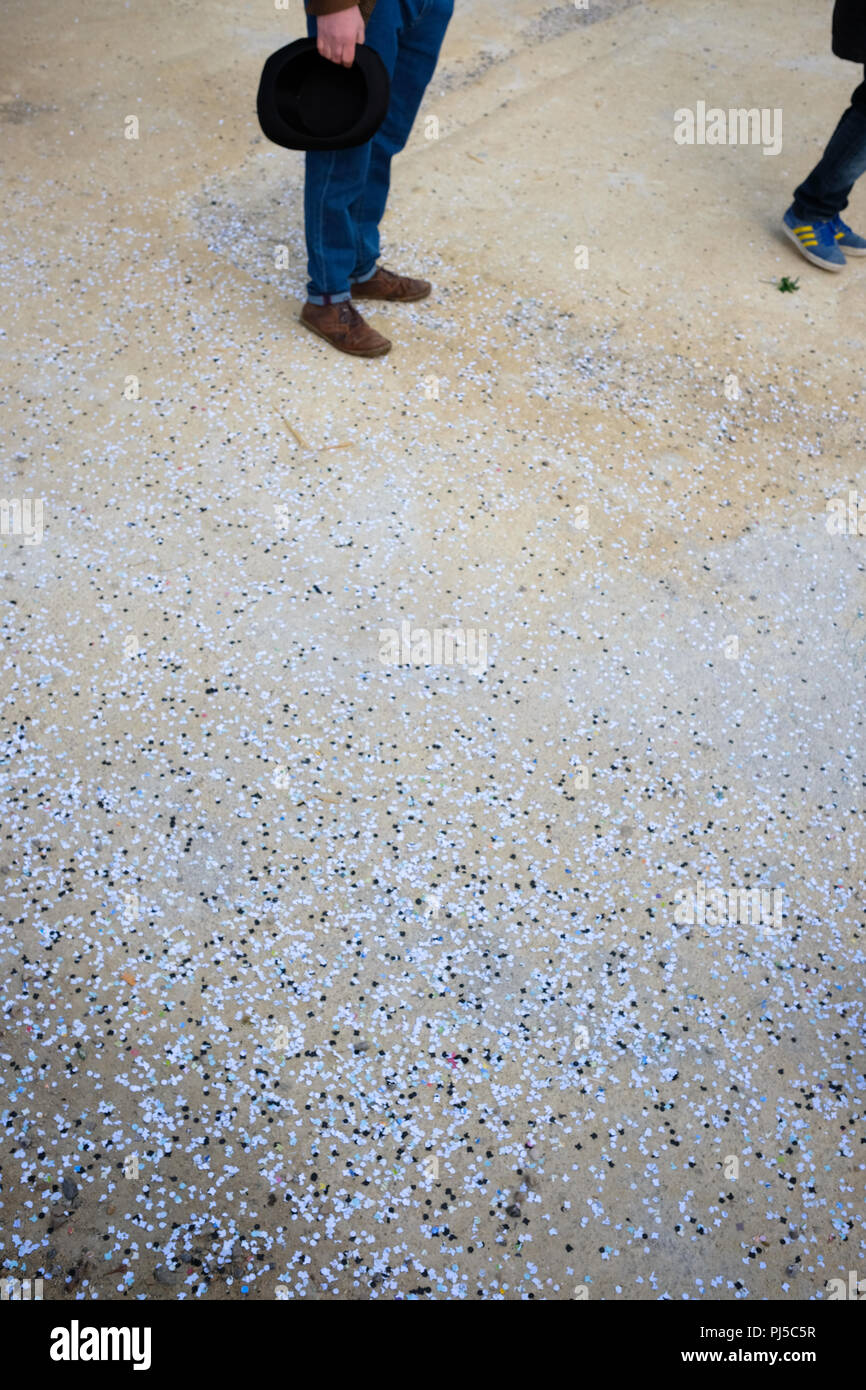 cropped view of two peoples legs and feet standing on the ground in park surrounded by multi-coloured paper confetti Stock Photo