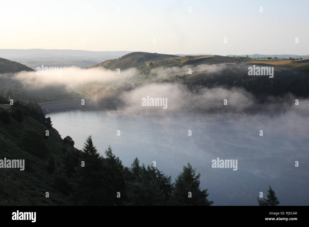 mist and sunshine over Llyn Clewedog reservoir, near Llanidloes, Powys, Mid Wales, UK, early morning in late August seen from the B4518 Stock Photo