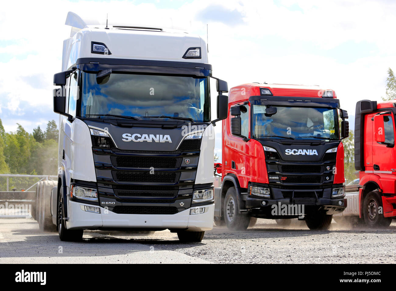 Next Generation Scania R650 (white) and R650 XT truck tractors (red) and wind blowing sand around lorries in Seinäjoki, Finland - August 11, 2018. Stock Photo