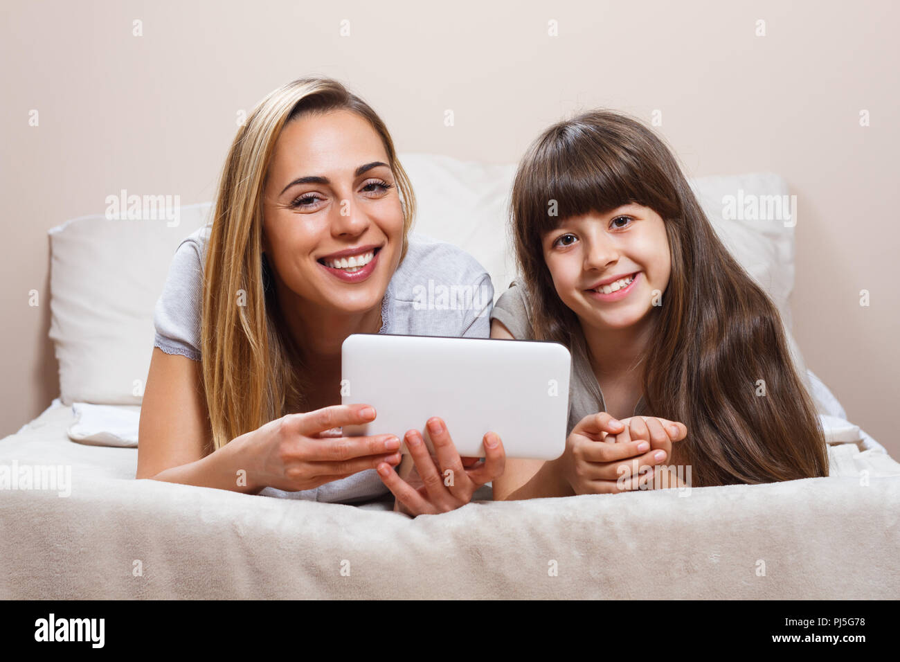 Mother and daughter using digital tablet in bed Stock Photo