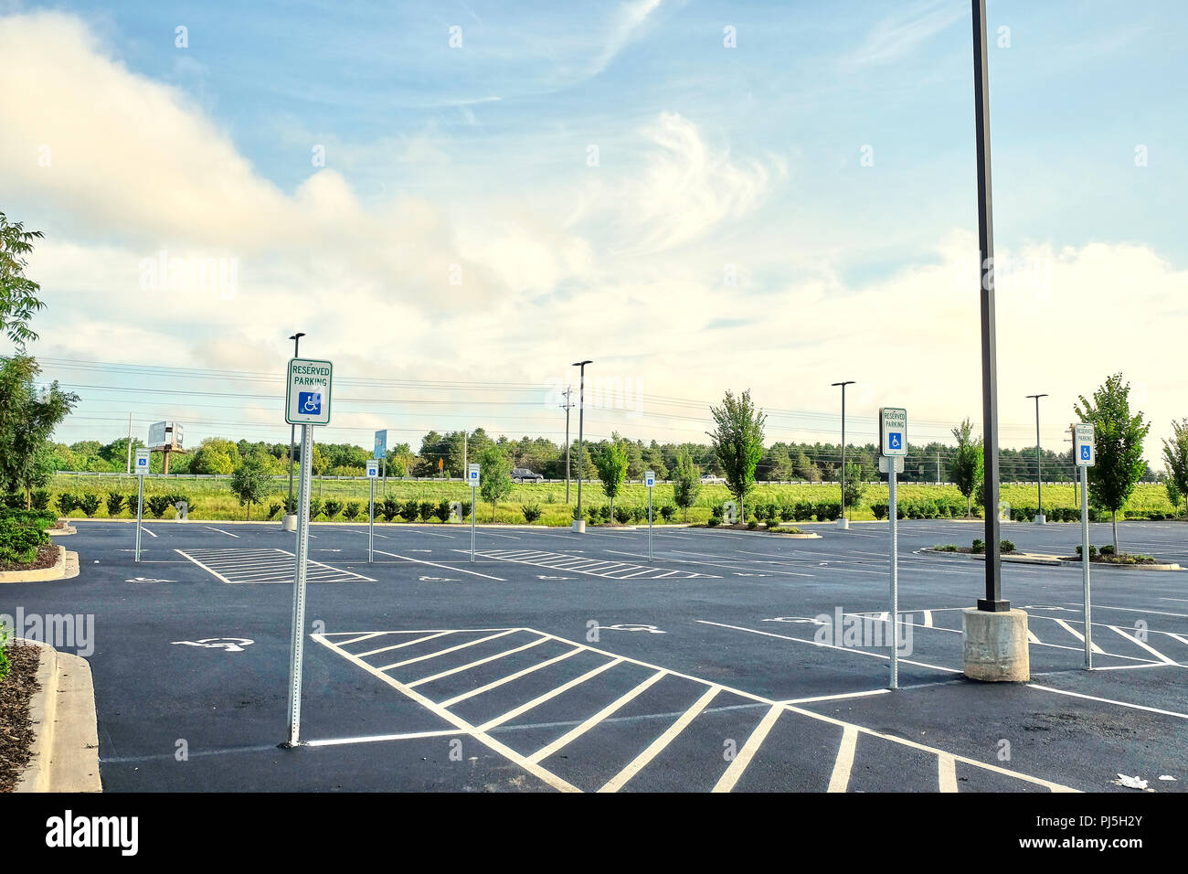 Multiple or numerous empty handicap parking spaces with warning signs in shopping center parking lot or car park in Montgomery Alabama, USA. Stock Photo