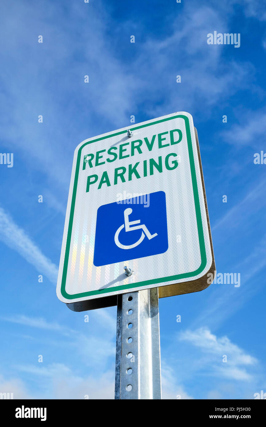 Handicap parking sign or disabled parking sign from low angle, isolated against blue sky. Stock Photo