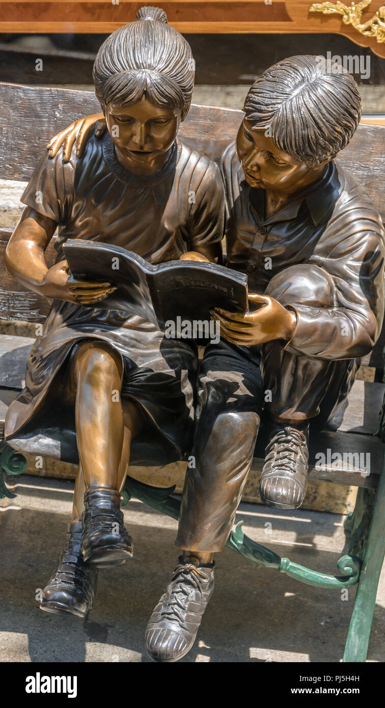 Bronze Sculpture Of Two Children Sitting On A Bench Reading A Book Taken In Chinatown San Francisco Stock Photo
