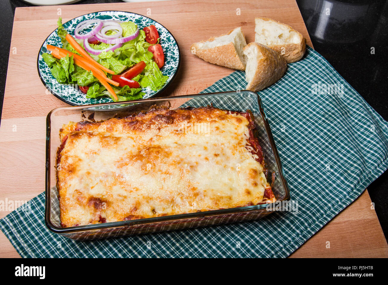 Baked lasagne in dish with salad and bread Stock Photo