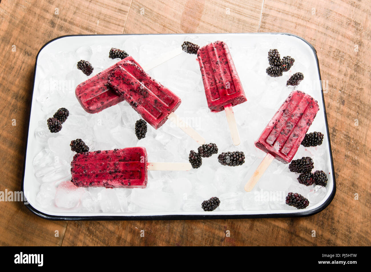 Frozen blackberry pops with berries on tray of ice Stock Photo