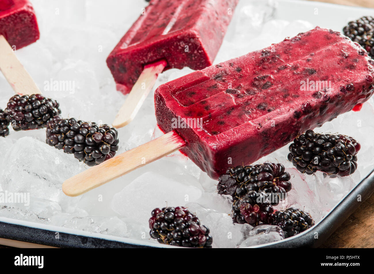 Frozen blackberry pops with berries on tray of ice Stock Photo