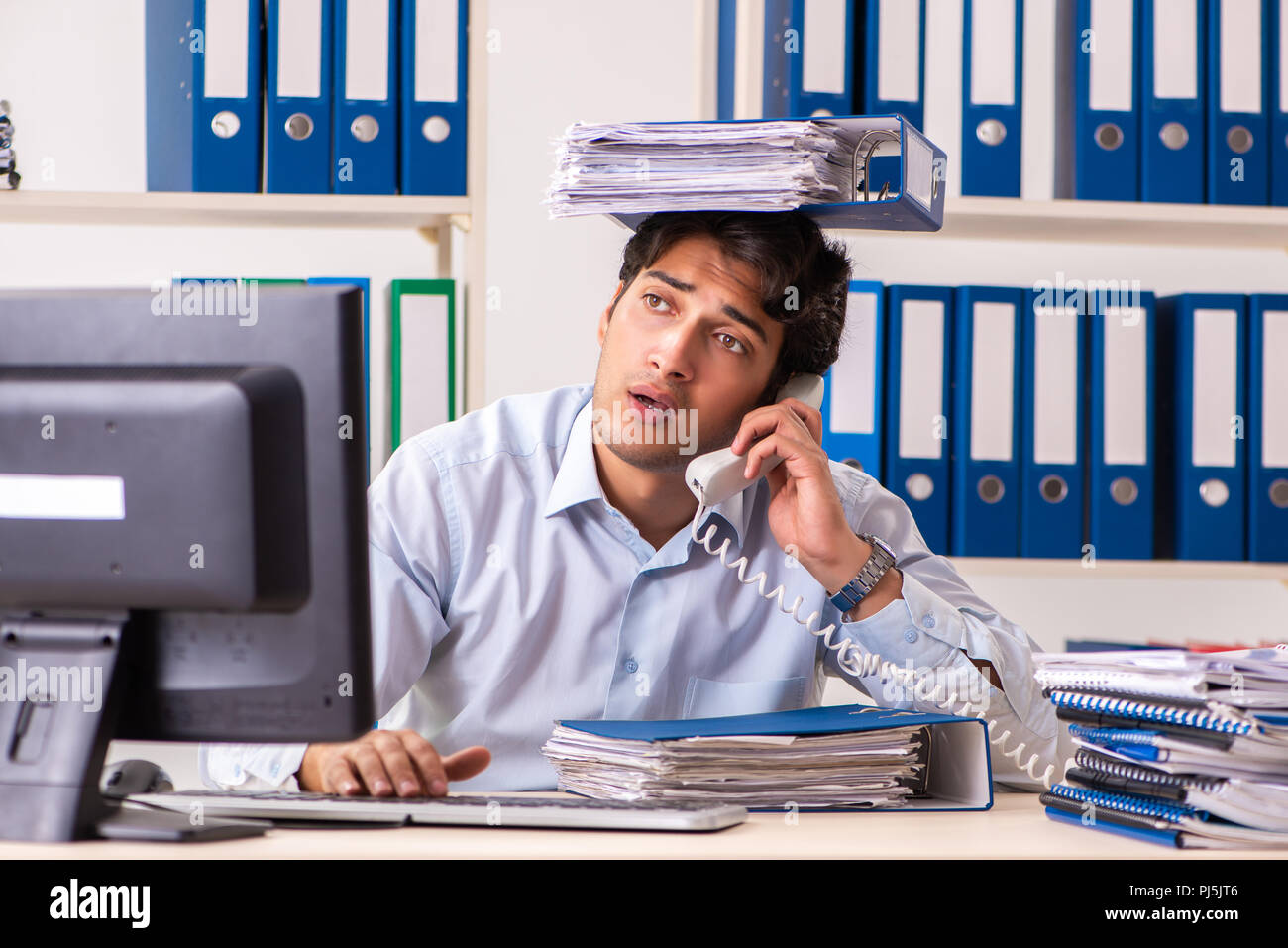 Overloaded busy employee with too much work and paperwork Stock Photo