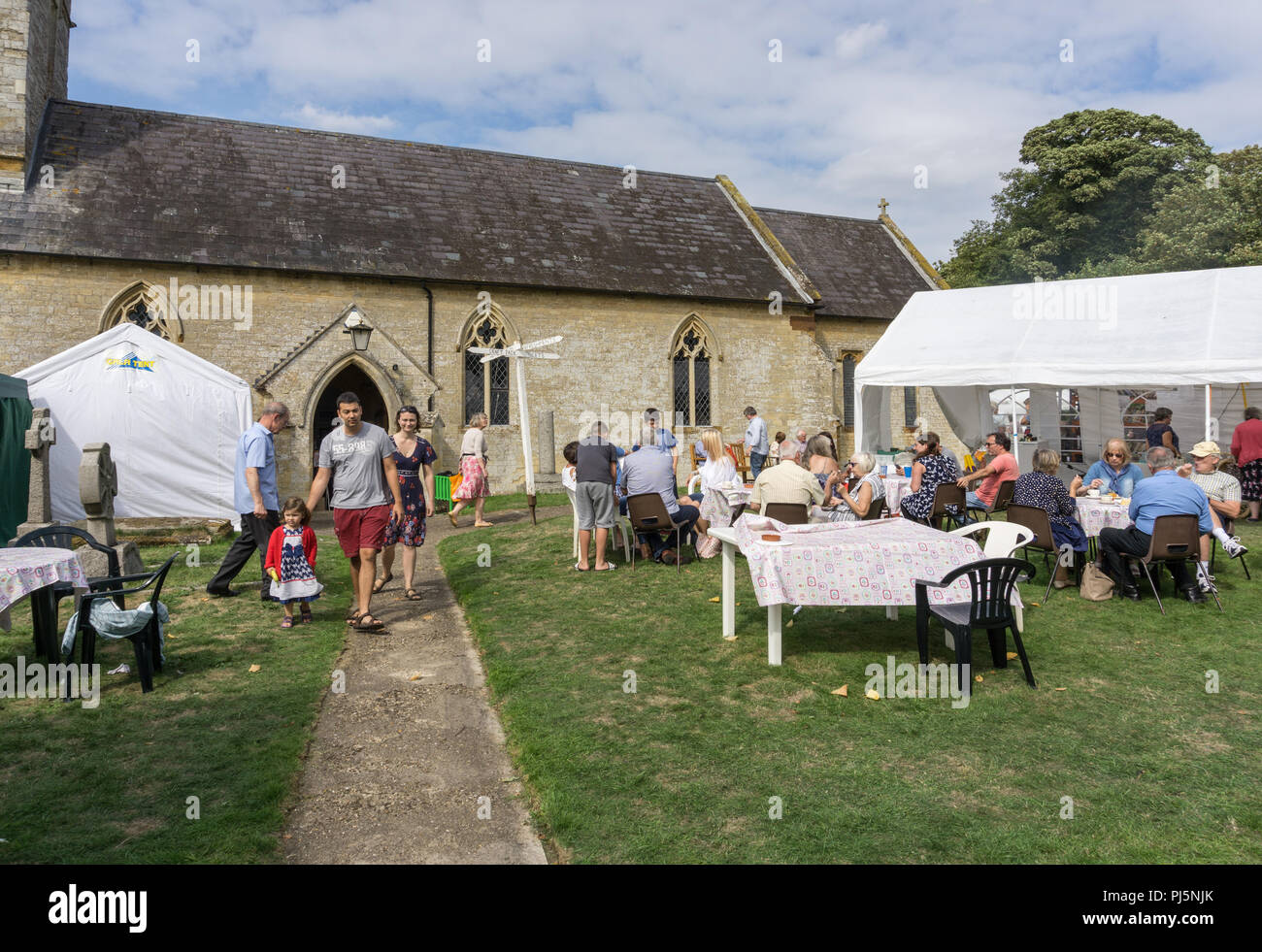 A summer afternoon and cream teas being served on the lawn in front of St Margaret's Church, Alderton, Northamptonshire, UK Stock Photo