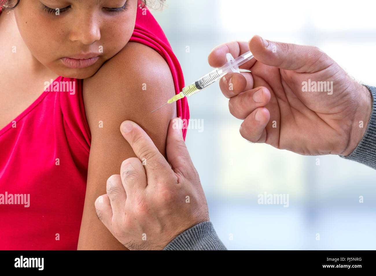 Vaccination. Young boy receiving vaccination immunisation by professional health worker, focus on shoulder Stock Photo