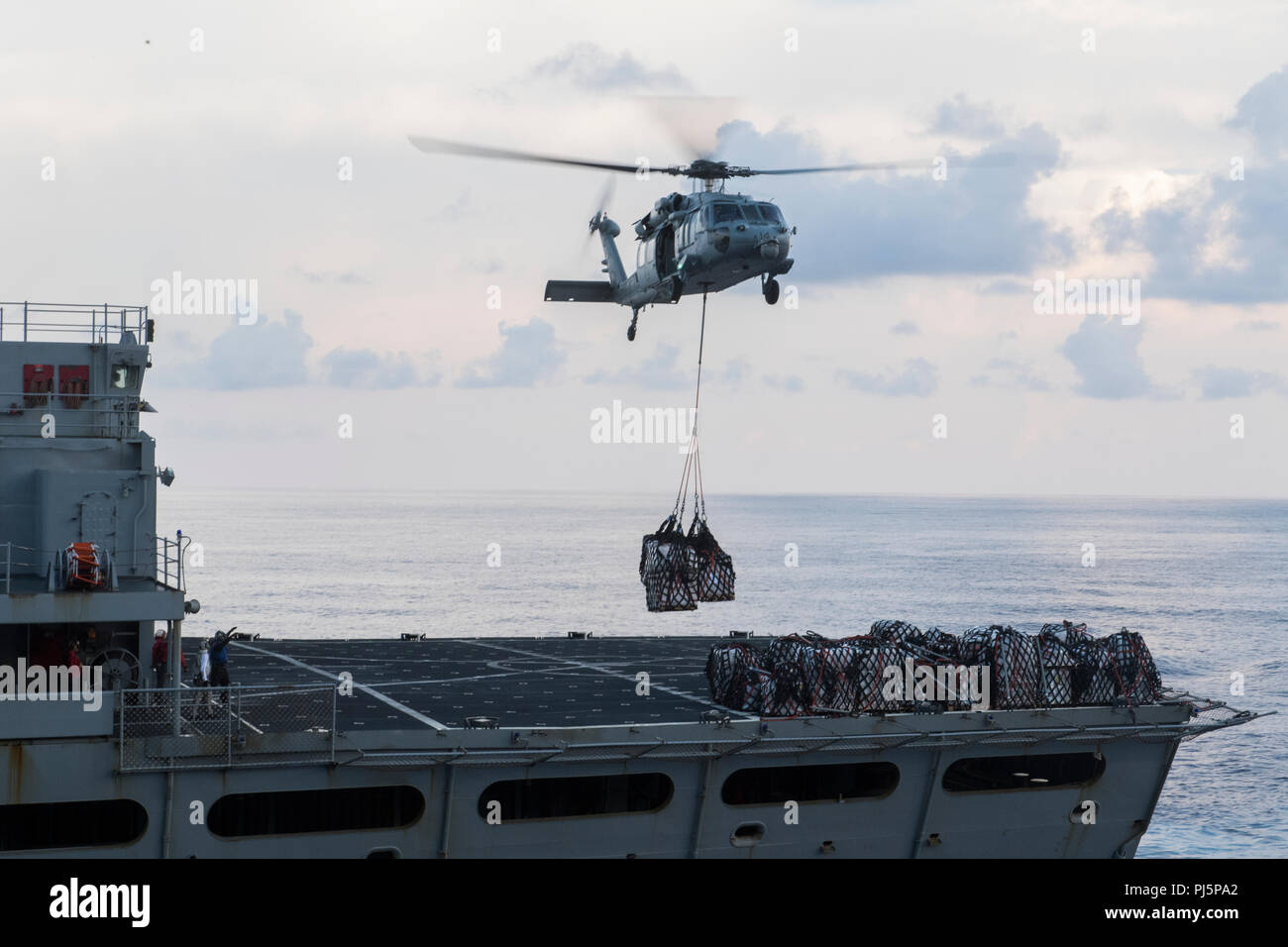 180824-N-TT202-076  ATLANTIC OCEAN (Aug. 24, 2018) An MH-60S Sea Hawk from the Dusty Dogs of Helicopter Sea Combat Squadron (HSC) 7 transports cargo from the fast combat support ship USNS Arctic (T-AOE 8) to the Nimitz-class aircraft carrier USS Abraham Lincoln (CVN 72) during a replenishment-at-sea. Abraham Lincoln is currently underway conducting carrier qualifications. (U.S. Navy photo by Mass Communication Specialist 3rd Class Daniel E. Gheesling/Released) Stock Photo