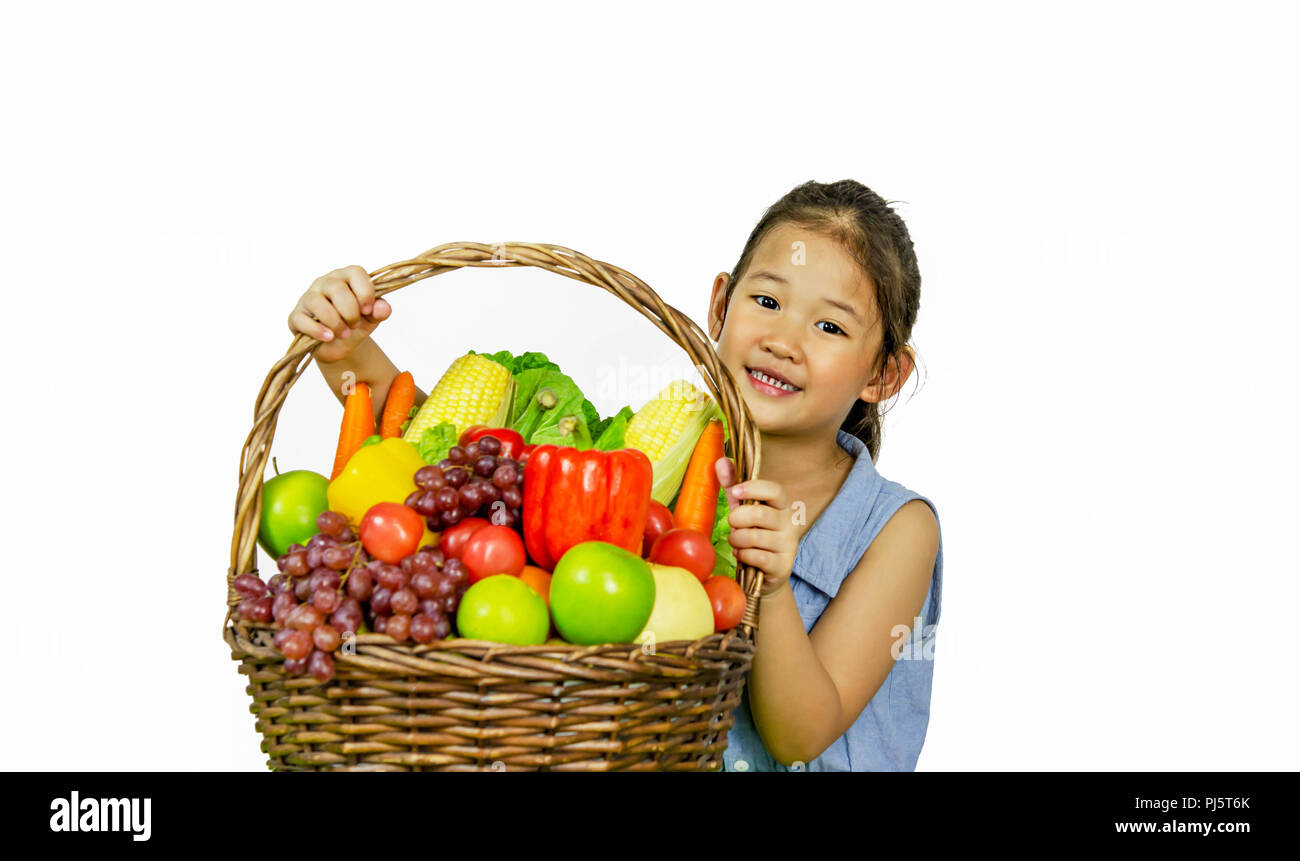 Smiling asian little girl with fruits and vegetables in basket over ...