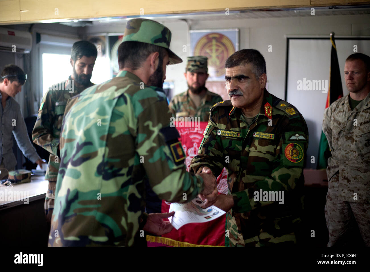 HELMAND PROVINCE, Afghanistan (August 26, 2018) – Afghan Brig. Gen. Abdul Hadi, Afghan National Army (ANA) 215th Corps deputy commander, hands an ANA soldier his certificate of completion during a graduation ceremony for a train-the-trainer course at the Regional Military Training Center on Camp Shorabak. The nearly month-long course taught instructors the basics of warrior training so they can, in turn, teach the upcoming classes of the new ANA Territorial Force who will assist in providing safe and secure elections to the people of Helmand and provinces this October. (U.S. Marine Corps photo Stock Photo