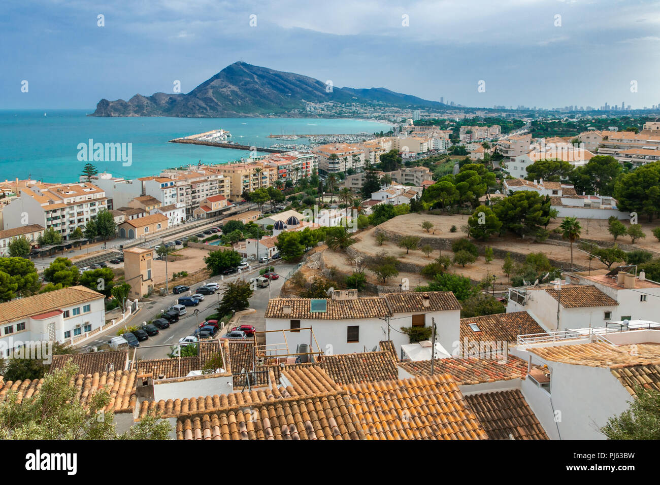View of the orange roofs of houses in the town of Altea, Valencia, Spain. In the distance, the Mediterranean, the Mount of Mount Ifach in Calpe. Stock Photo