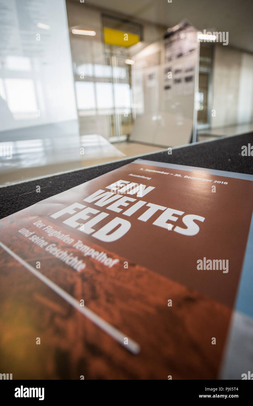 04.09.2018, Berlin: A poster with the inscription 'Ein weites Feld. Tempelhof Airport and its History' (lit. A wide field - Tempelhof Airport and its history) is located next to a glass pane in the Tempelhof airport building. In the exhibition 'A wide field - Tempelhof Airport and its history' in the departure terminal, visitors can obtain information about the history of the airport on the basis of photos. The exhibition is open to visitors from 5 September to 30 December 2018. Photo: Wolfgang Kumm/dpa Stock Photo