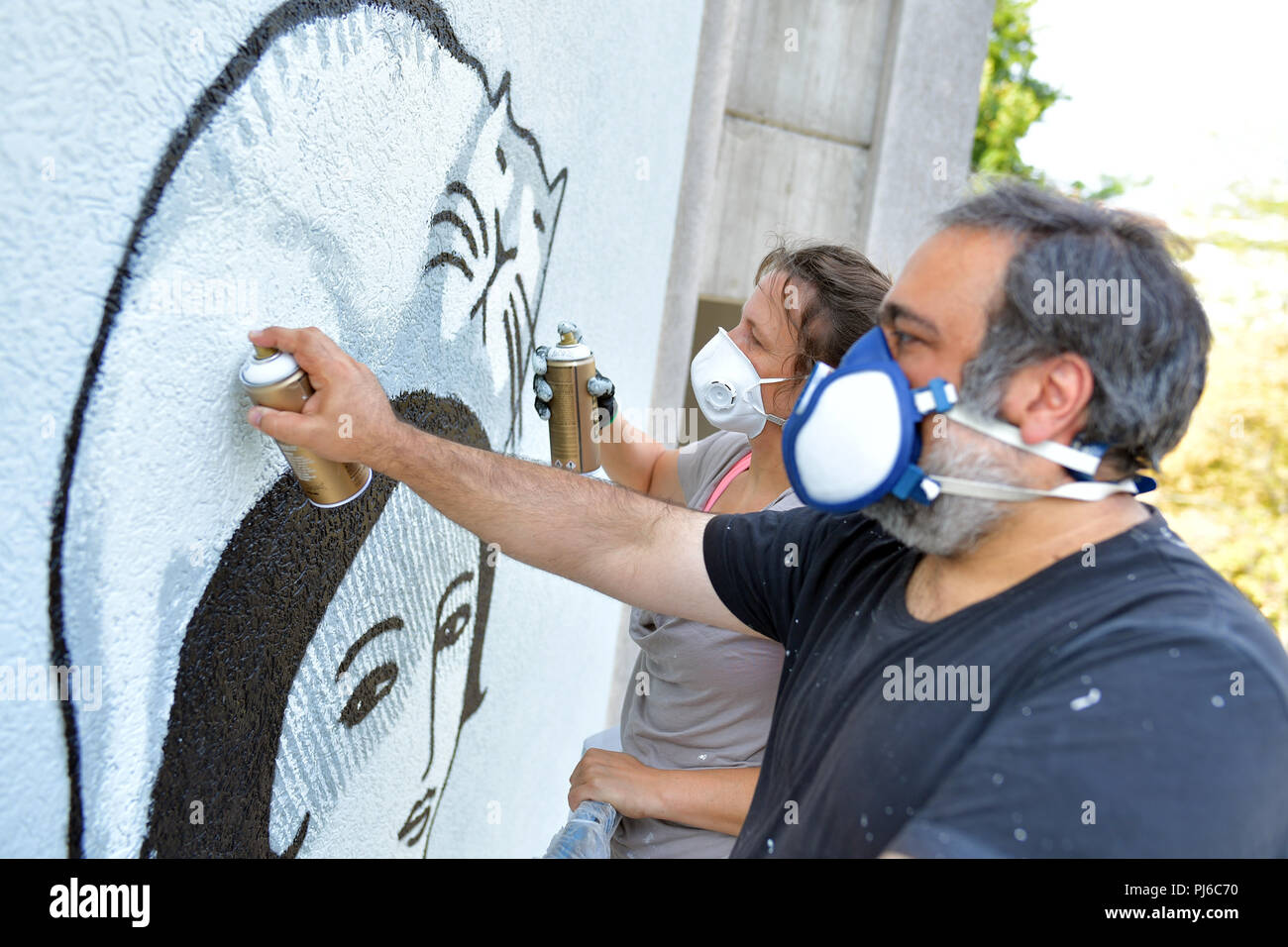 Mannheim, Germany. 23rd Aug, 2018. 23.08.2018, Baden-Württemberg, Mannheim: Christina Laube (l) and Mehrdad Zaeri from the artist duo 'Sourati' spray a mural entitled 'Abschied und Neubeginn' (lit. Farewell and New Beginning) on a house wall. At the end of the year, 18 huge works of art will be displayed on the facades of the North Baden city. Credit: Uwe Anspach/dpa/Alamy Live News Stock Photo
