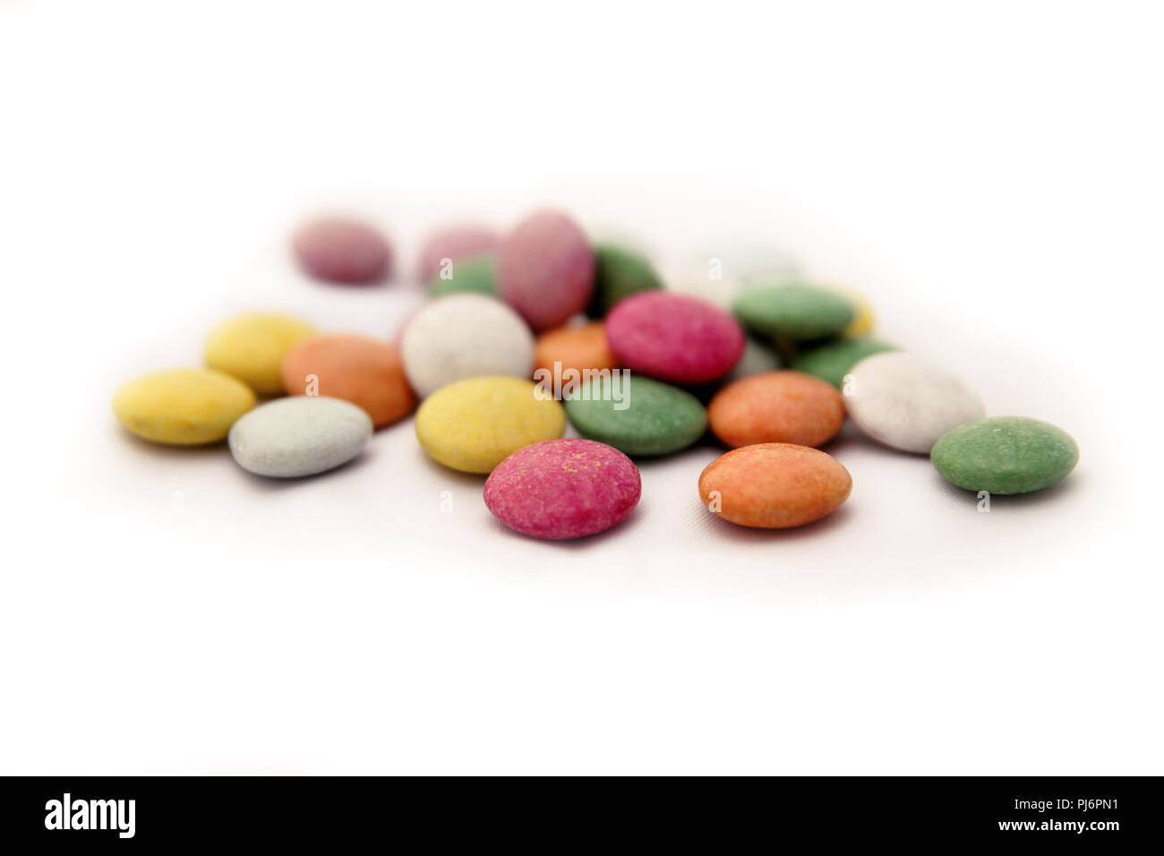 Colored candy. Multicolored colorful candy with white background closeup. Colorful chocolate button candies spread randomly on white background. Stock Photo